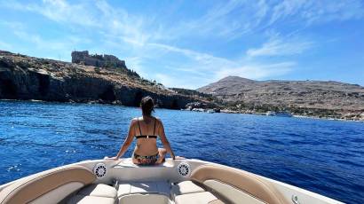 Happy guest enjoying a private skippered tour in Lindos on a Sea Ray 260 speed boat